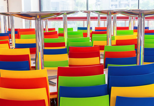 Kapalı bir kafede çok renkli plastik sandalyeler ve masalar. - Fotoğraf, Görsel