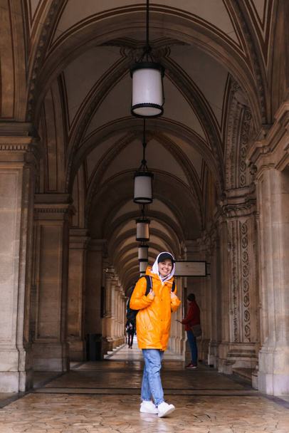 mujer turista caminando con mochila en impermeable amarillo ciudad turismo copia espacio
 - Foto, imagen