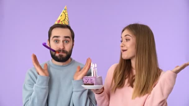 Cheerful young lovely couple having fun on birthday party over purple background - Filmmaterial, Video