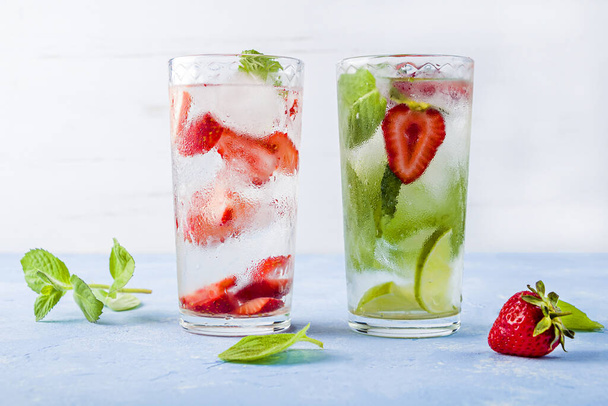 Two glass of refreshing cool detox drink with strawberry, lime and mint on blue background. Various summer lemonades or ice tea. Mojito cocktail with ice cubes. Healthy eating. copy space for text       - Foto, Bild