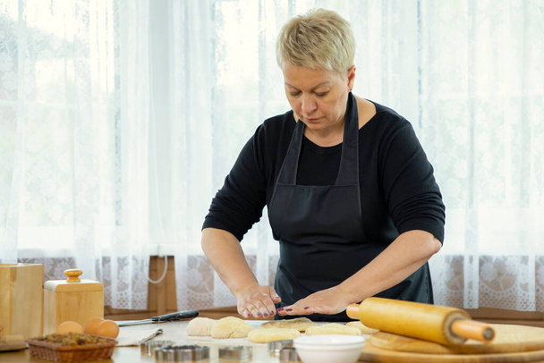 middle-aged woman making homemade cookies and pastry kneading dough - Foto, Imagem
