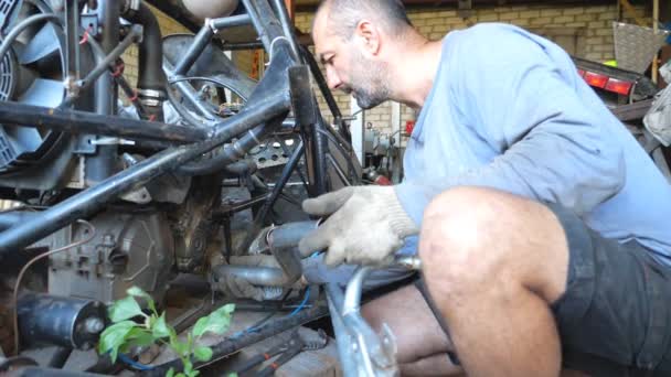 Adult mechanic repairing vehicle. Attentively repairer fixing automobile. Auto master doing his work in garage or workshop. Man engaged servicing auto. Slow motion Close up - Footage, Video
