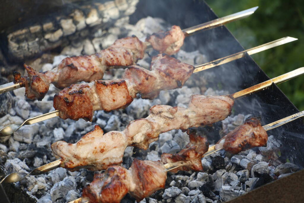 Cooking barbecue skewers. Marinated kebab is grilled on charcoal. Shish kebab barbecue was made of lamb, pork, beef, chicken. Roast beef skewers on barbecue grill. Skewers on skewers. - Zdjęcie, obraz