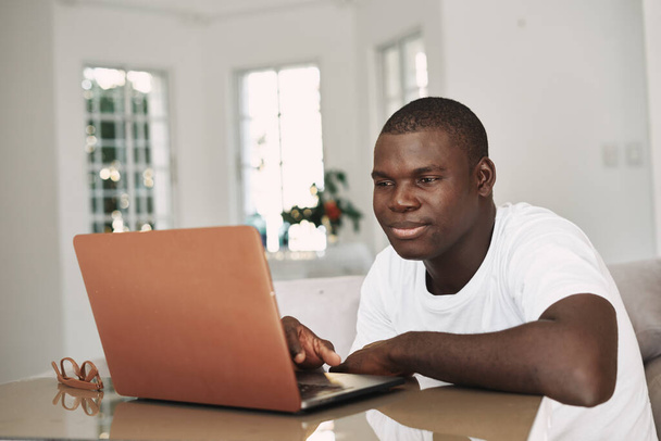 Un uomo sta guardando un computer portatile in casa freelance - Foto, immagini