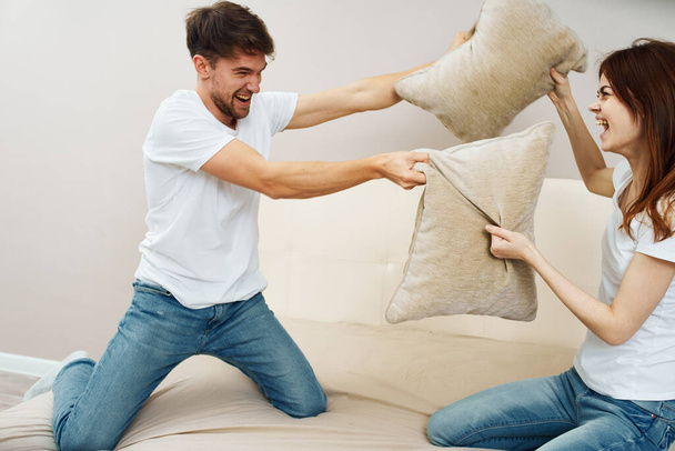 A woman and a man fight pillows on the sofa  - Foto, Imagem