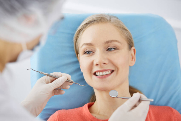 Smiling caucasian woman is being examined by dentist at dental clinic. Healthy teeth and medicine, stomatology concept - Photo, Image