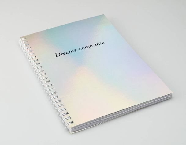 een notitieboekje met iriserende omslag en motiverende tekst, witte achtergrond - Foto, afbeelding