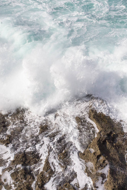 Bay of Biscay. Raging force of nature. Waves lick stones and beat against rocks. Spanish coast. Salty sea air. Boulders and stones in the spray of sea waves. Seascape view from above. Sound of waves. Foam of waves on a stone block. - Photo, Image