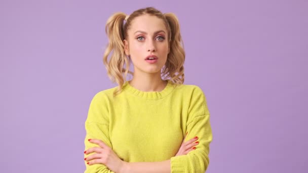 A pensive beautiful girl does not agree to the proposal proposed to her, negatively waves her hand in different directions in an isolated studio on a purple background - Felvétel, videó