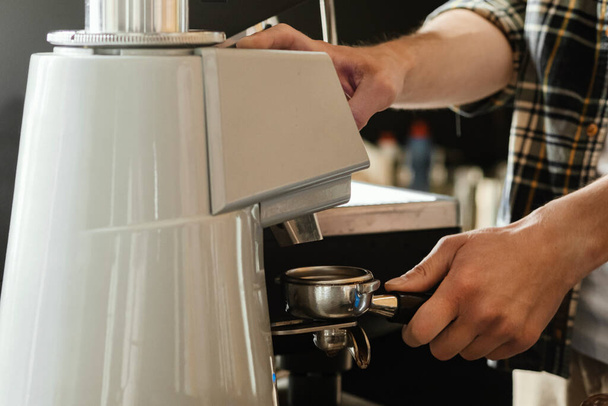 Closeup of barista grinding coffee. Professional barista working makeing coffee with coffee machine. Hot pouring drink concept. Toned picture - Φωτογραφία, εικόνα