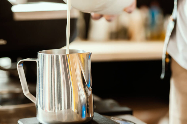 Barista ρίχνει το γάλα σε μια κανάτα από ανοξείδωτο χάλυβα γάλα. Latte τέχνη για barista. Αξεσουάρ καφέ. Σετ Barista.  - Φωτογραφία, εικόνα