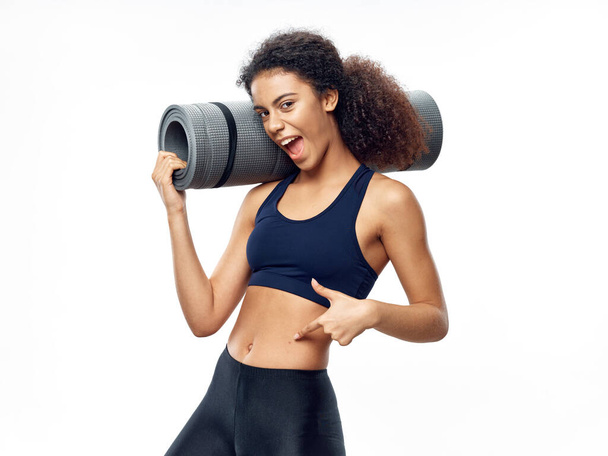 A sporty woman with a slim figure holds a fitness mat  - Foto, Imagem