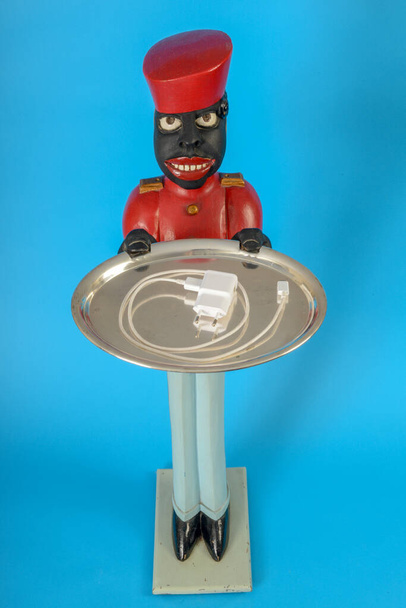 Statue eines schwarzen Dieners mit Ladekabel auf einem Tablett - Foto, Bild