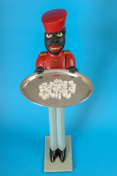 Άγαλμα μαύρου υπηρέτη με χάπια στο δίσκο. - Φωτογραφία, εικόνα