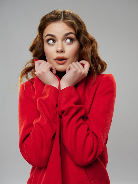 Surprised woman in a red sweater looks sideways  - Zdjęcie, obraz