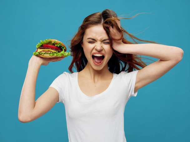 Energická žena se širokými ústy drží hamburger  - Fotografie, Obrázek