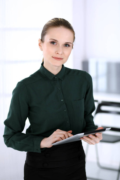 Business woman headshot in modern office. Secretary or female lawyer using tablet computer while standing straight. Business people concept - Foto, imagen