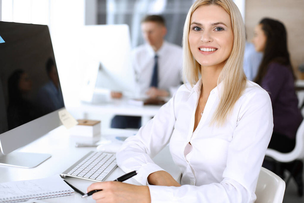 Business woman using computer at workplace in modern office. Secretary or female lawyer smiling and looks happy. Working for pleasure and success - Zdjęcie, obraz