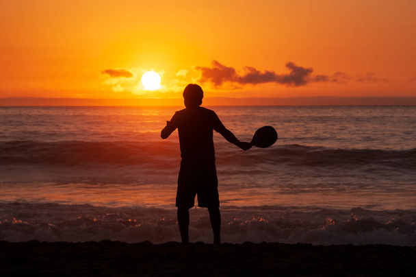 A boy plays beach tennis at sunset by the sea on the Central coast of Chile - Photo, Image