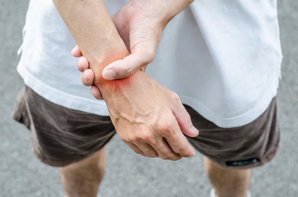 Wrist pain. Male holding hand to spot of wrist pain. - Photo, Image