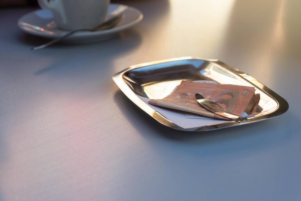 πληρωμή με δέκα ευρώ στο δίσκο για τους καφέδες που λαμβάνονται στη βεράντα της καφετέριας σε μια καλοκαιρινή ημέρα - Φωτογραφία, εικόνα