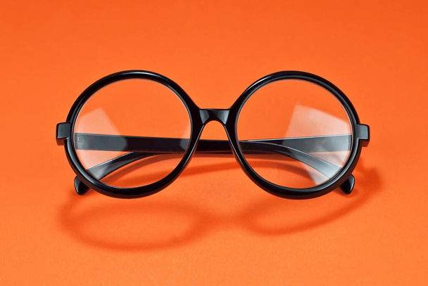 Різні типи окулярів на помаранчевому тлі крупним планом. Окуляри з круглими рамками
.  - Фото, зображення