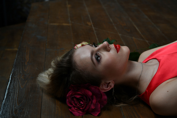 piękna dziewczyna wieczorem czerwona sukienka leży na podłodze na czarnym tle - Zdjęcie, obraz
