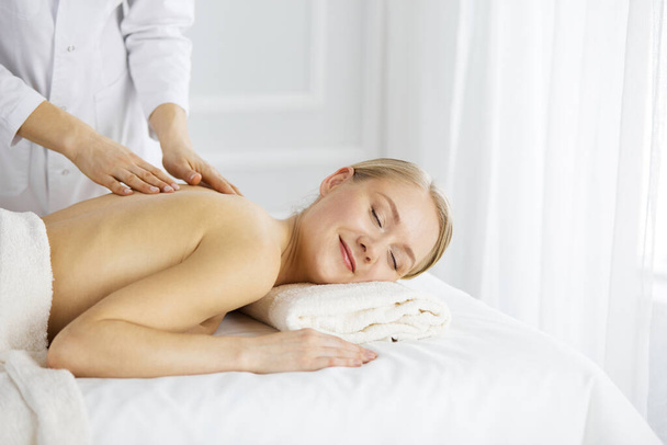 Beautiful caucasian woman enjoying back massage with closed eyes. Beauty and Spa salon concept - Foto, Imagem