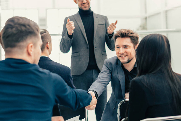 funcionários sorridentes apertando as mãos durante uma reunião de trabalho - Foto, Imagem