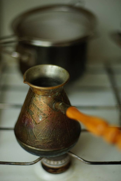 acero inoxidable turco sucio con patrón de grabado y mango de madera en una estufa de gas
. - Foto, imagen
