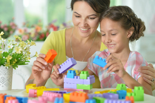  little daughter and mother playing with colorful plastic blocks at home - Fotoğraf, Görsel