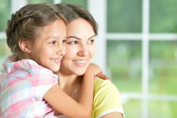 Close-up portrait of a charming little girl hugging with mom at home - Фото, зображення