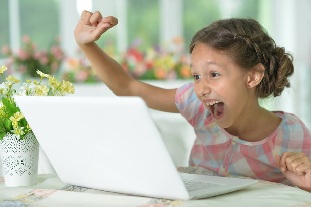 Emocional chica linda feliz usando el ordenador portátil en casa
 - Foto, imagen