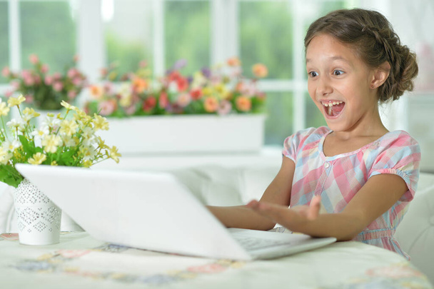 Emotional  surprised cute girl using laptop at home - Фото, изображение
