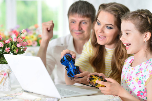 parents and daughter using laptop playing game - Fotó, kép