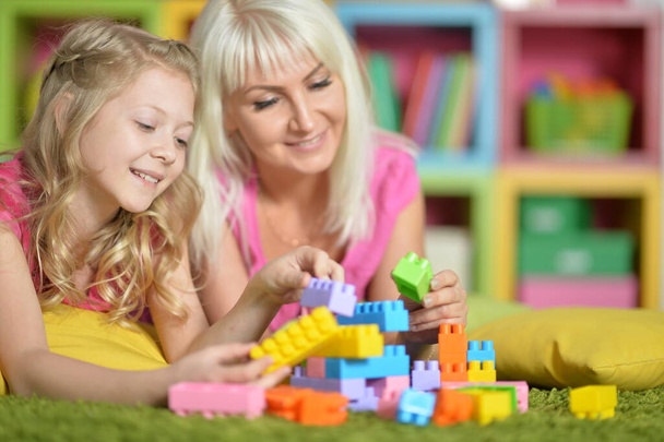  little daughter and mother playing with colorful plastic blocks at home - Photo, image