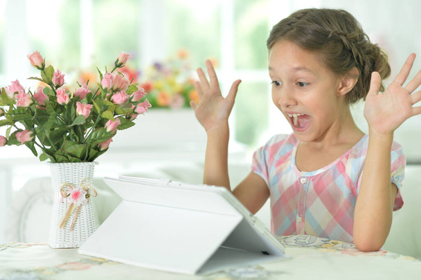 Portrait of  Beautiful little surprised  girl with tablet pc - Fotó, kép
