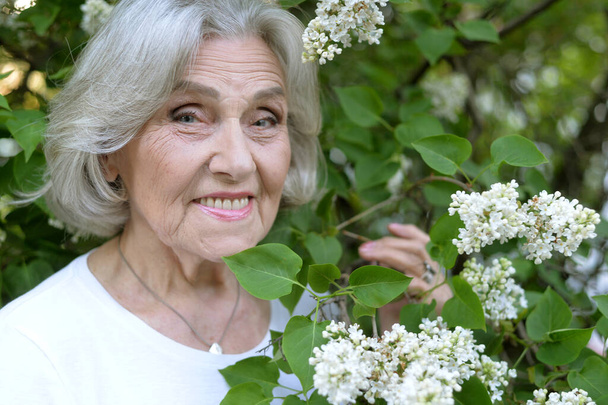  senior beautiful woman with lilacs in   park - Φωτογραφία, εικόνα