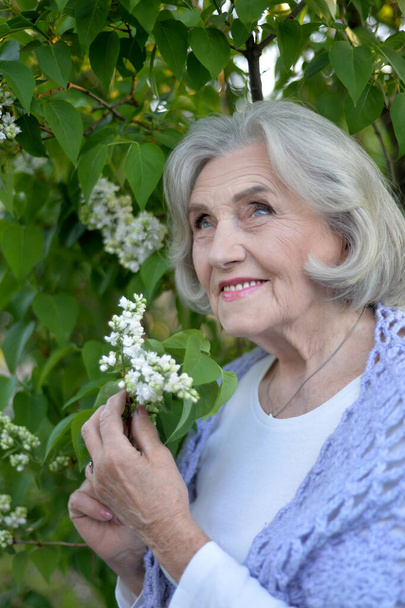  senior beautiful woman posing with lilacs in   park - Photo, image