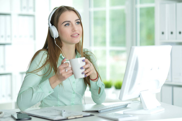 Portrait of  businesswoman working in headphones  in office - Zdjęcie, obraz