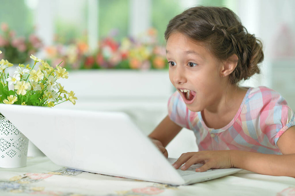 Emotional surprised cute girl using laptop at home - Foto, imagen