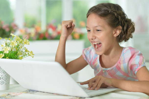 Emotional happy cute girl using laptop at home - Foto, imagen