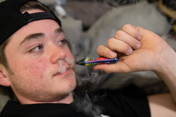 adolescente está exalando fumaça de vape com conteúdo de THC - Foto, Imagem