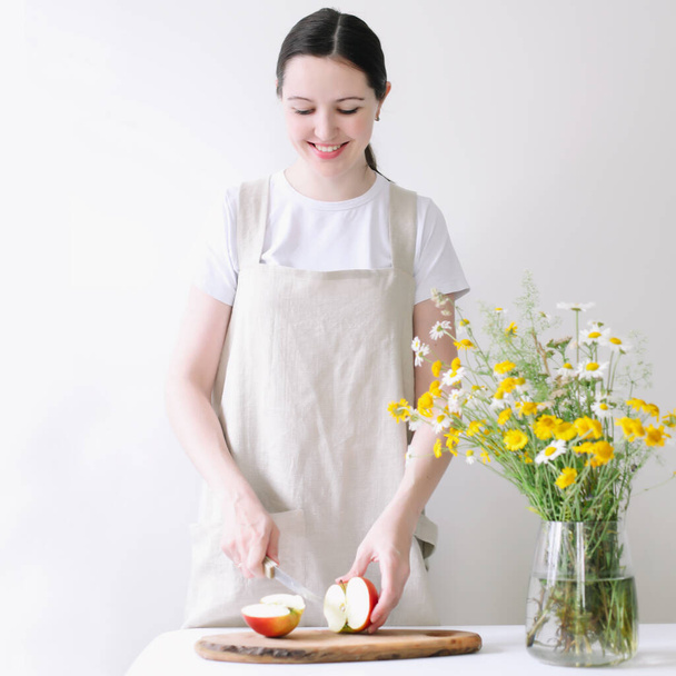 Woman in linen apron cooking in the kitchen. Food blogger concept, homemade cooking, rustic style - Φωτογραφία, εικόνα