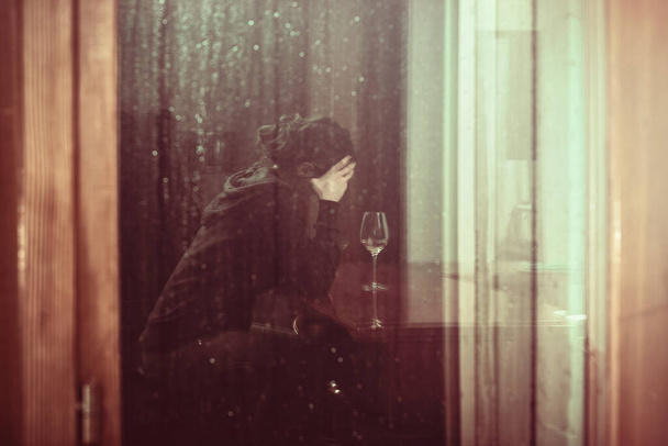 trieste en dronken vrouw binnen met een glas wijn, warme toon foto van een trieste jonge dame thuis - Foto, afbeelding