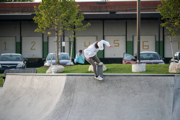 Detroit, Michigan, USA - 10.07.2019: Skaters and bikers practice tricks at sunset in the skate park in Detroit - 写真・画像