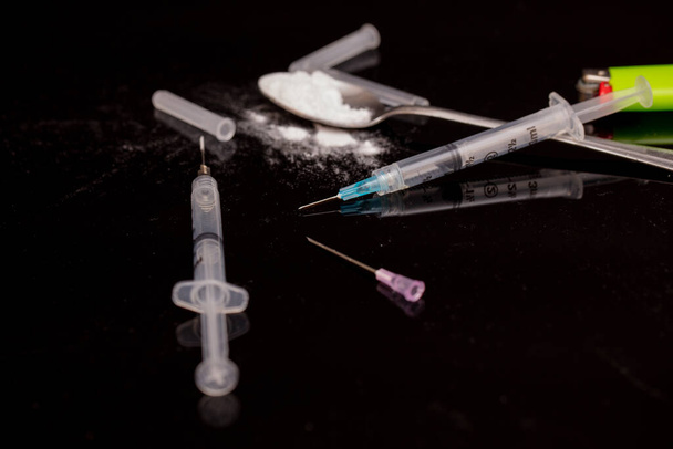 syringe with drug addiction and medical equipment on black background - Photo, Image