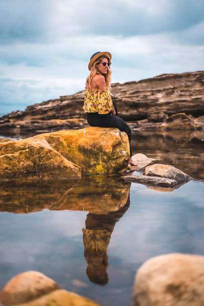 Portrait of attractive woman with long blonde hair at rocky shore. Fashion and travel - Foto, Imagen