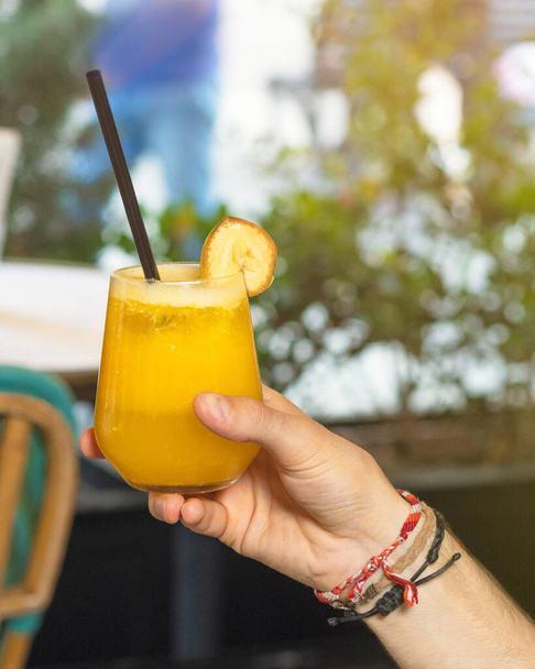 Человек держит апельсиновый сок в ресторане
 - Фото, изображение