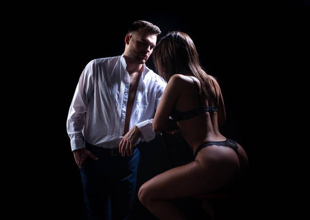 Passion couple on a black background. Pretty young couple of undressed sensual woman with beautiful straight body in lace erotic lingerie posing on dark background. - 写真・画像